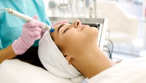 professional female cosmetologist doing hydrafacial procedure in cosmetology clinic. doctor use hydra vacuum cleaner. rejuvenation and hydratation. cosmetology